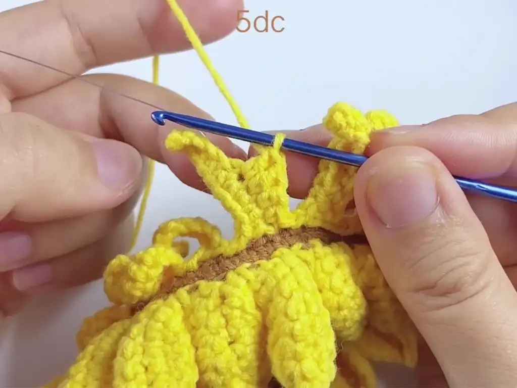 Attaching the second layer of petals to the crochet sunflower.