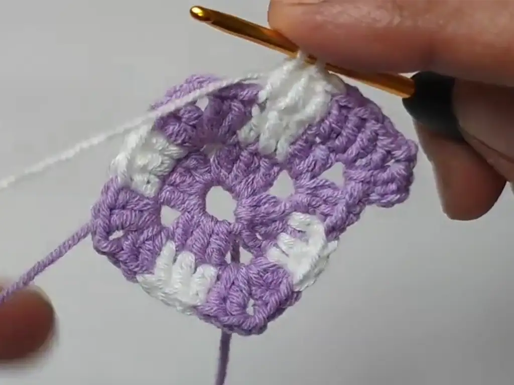 A step-by-step guide to crocheting a double crochet stitch, a key stitch in the granny square pattern.