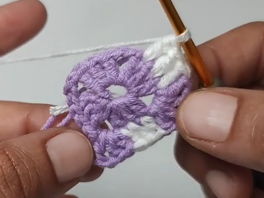 A step-by-step guide to crocheting a double crochet stitch, a key stitch in the granny square pattern.