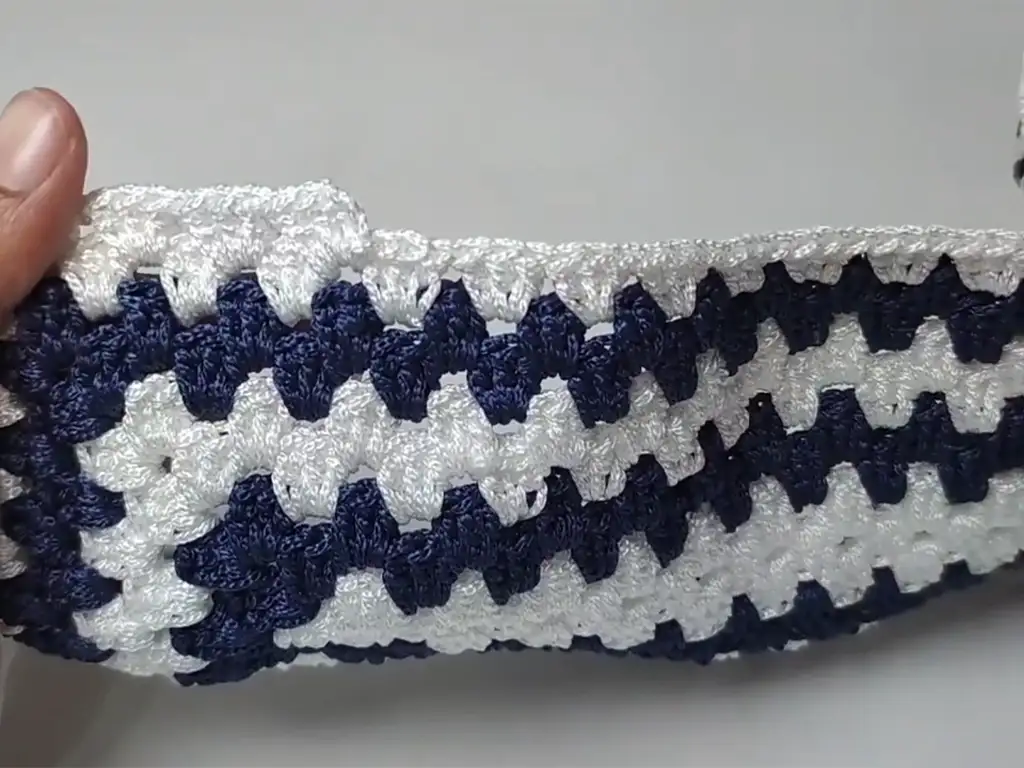 Crocheting the oval shape of a macrame beach tote bag, demonstrating the seamless transition from the rectangular base.