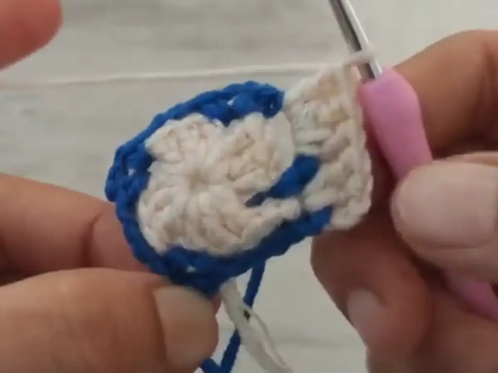 Demonstrating the color change process in crochet baby booties.