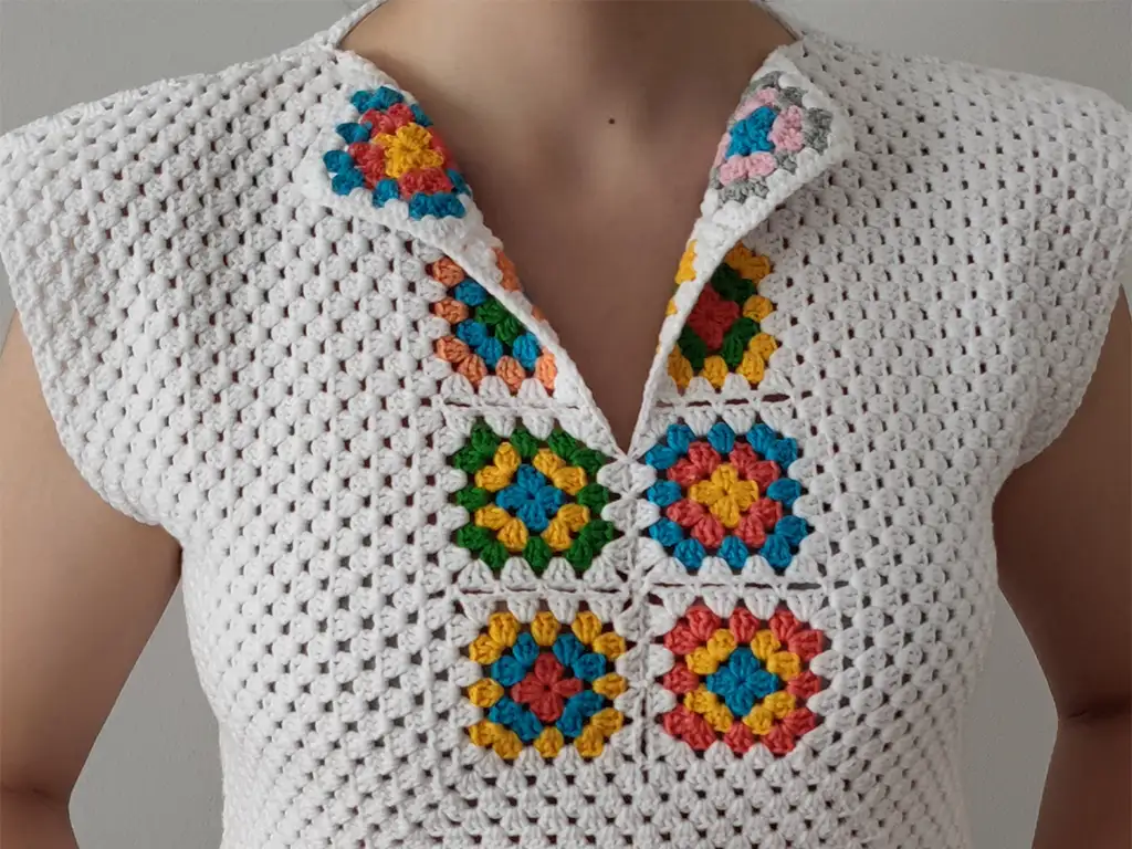 Stylish crocheter wearing a handmade, cream-colored crop top with a V-neckline made from granny squares.