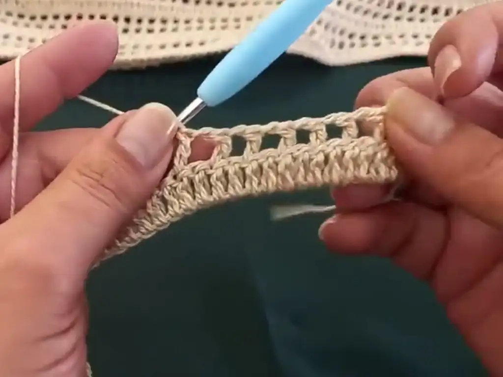 A partially finished crochet blouse panel, showcasing the progress of the easy stitch pattern and the open, airy fabric.