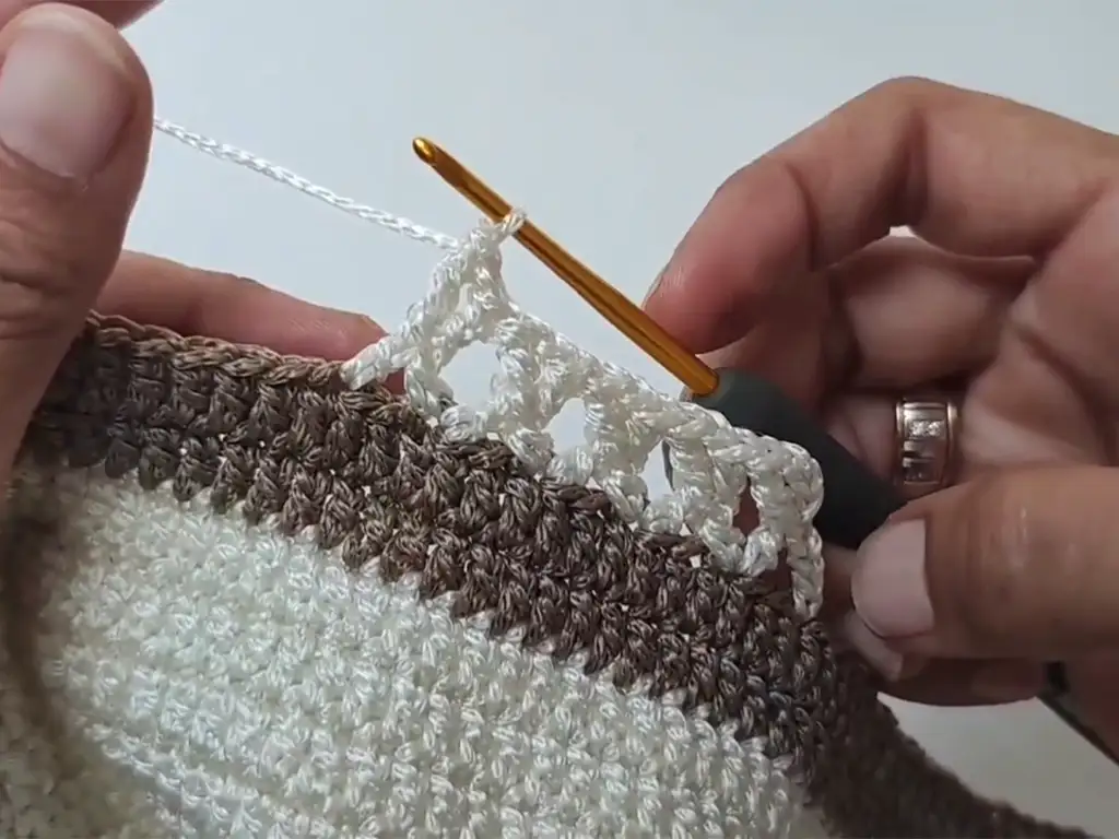 Crocheting the unique cross stitch pattern with cream macrame yarn for the tote bag.