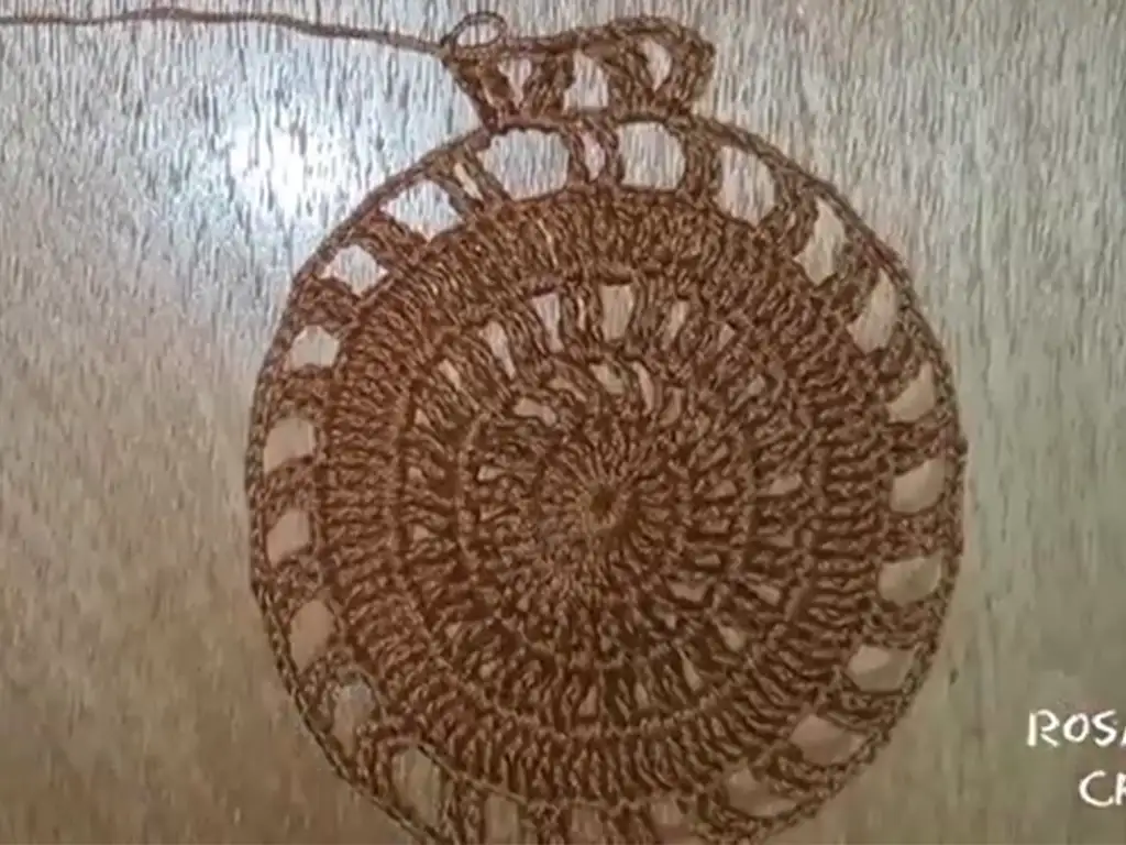 A fully crocheted brown circle motif with openwork details, demonstrating the intricate design of this element in a crochet dress.