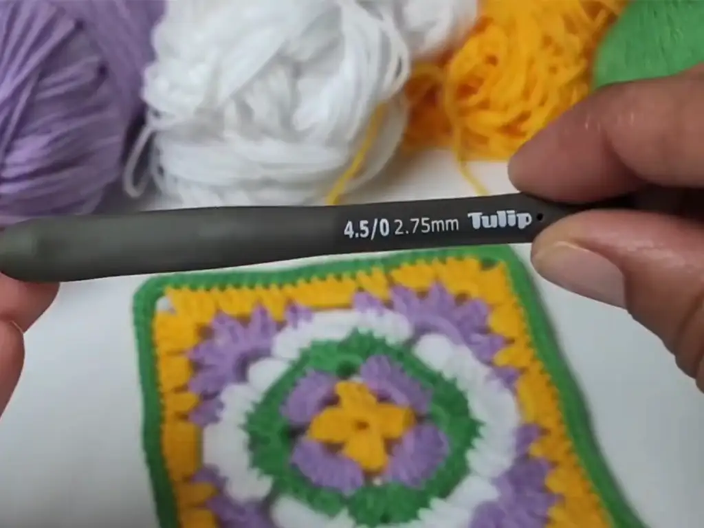 Close-up of a 2.75mm crochet hook and colorful yarn, ready to start a granny square pattern.