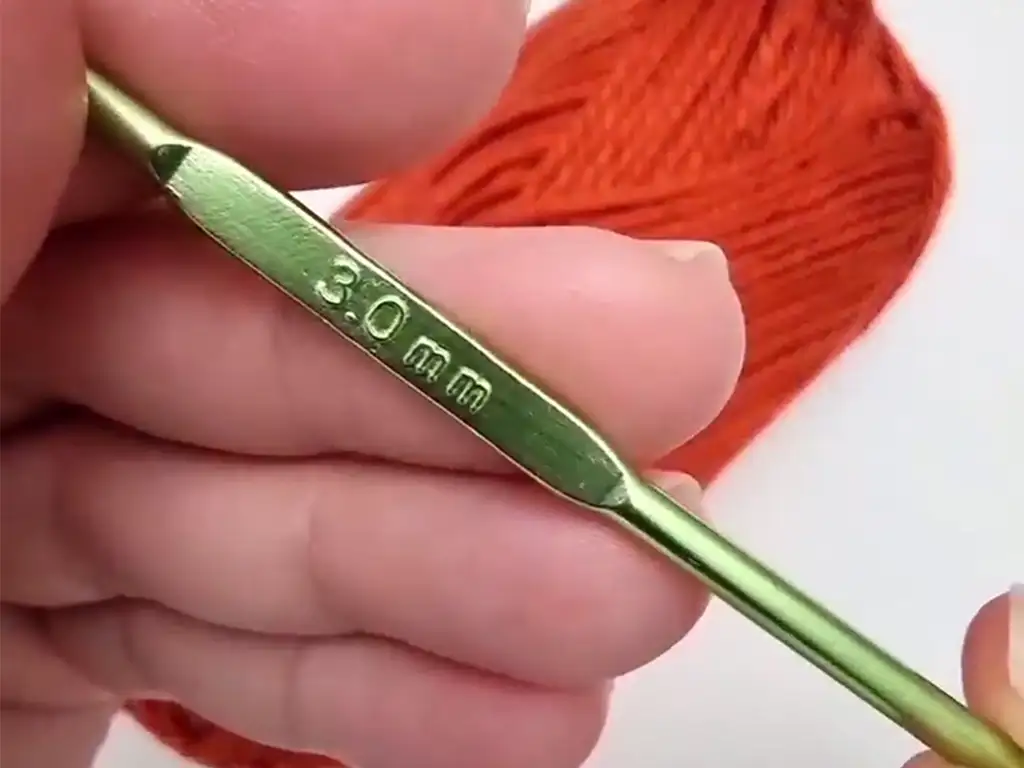 A 3.0mm crochet hook and orange yarn, the materials needed for the headband.