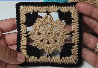 Close-up of a finished crochet square motif in beige and black yarn.