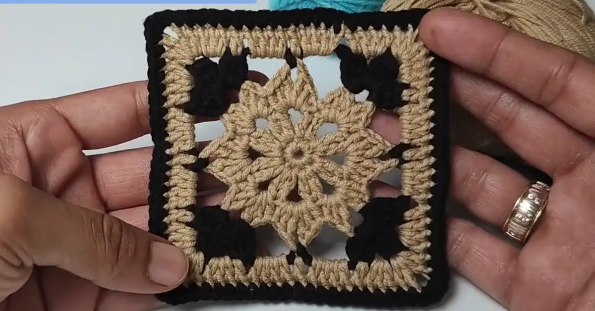 Close-up of a finished crochet square motif in beige and black yarn.