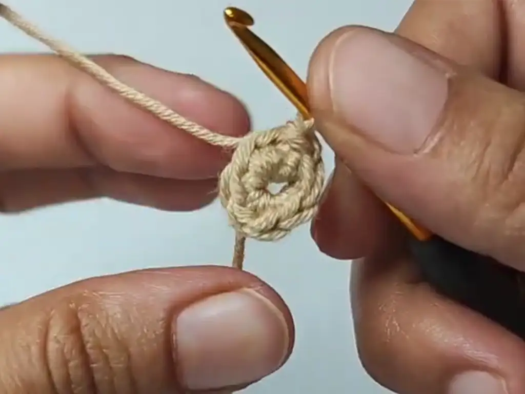 Completed first round of the crochet square pattern, forming a small circle.