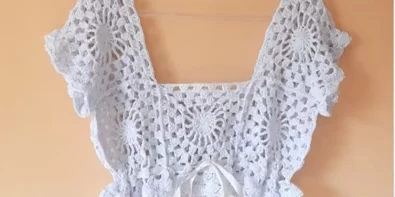 Completed crochet top made with granny squares, featuring a square neckline and short sleeves.