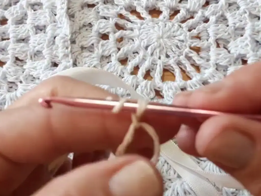 Close-up of crochet hook and yarn, starting a granny square for a free crochet top pattern.