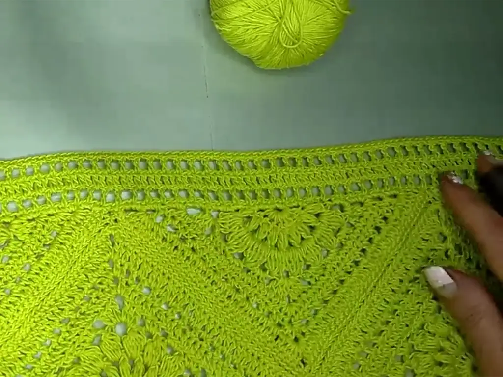 Close-up of the scalloped edging on a lime green crochet top.