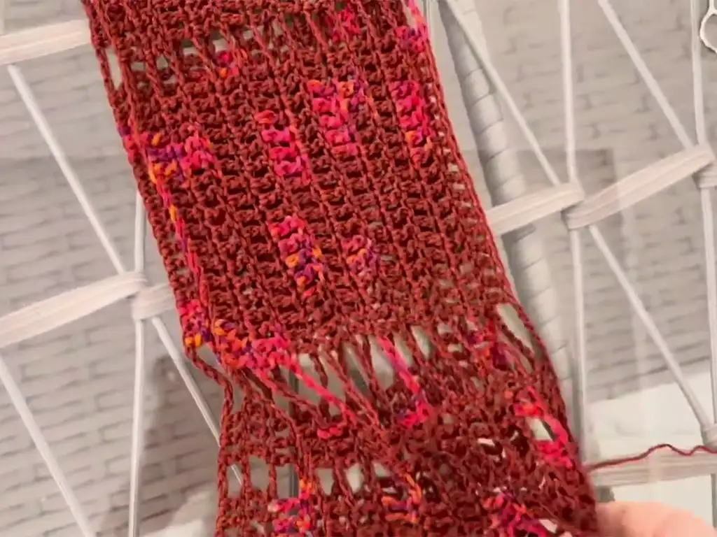 Close-up of crochet fabric with intricate open stitch pattern.