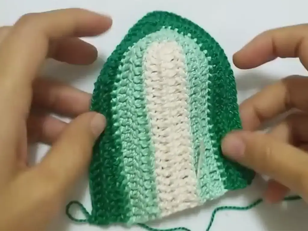 A half-finished crochet cropped top cup showing its curved shape.