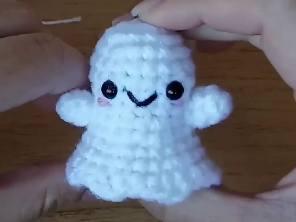 A close-up of a stuffed crochet ghost keychain.