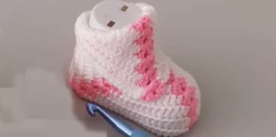 Pink and white crochet baby booties with a granny square design.