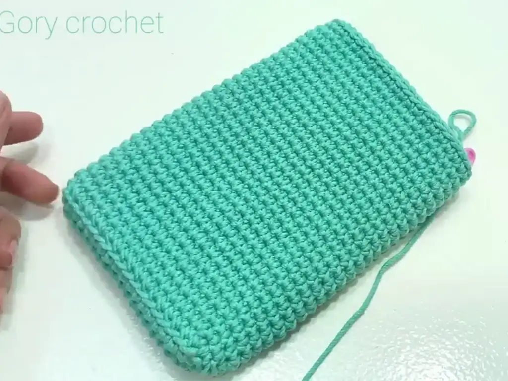 The crochet phone case body completed, showing the textured stitch pattern and turquoise color.