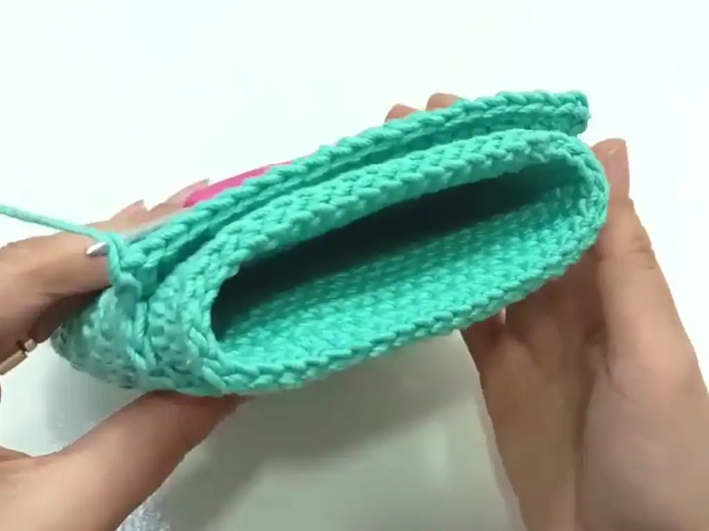Demonstrating how fold the top part of the crochet phone case create the flap.