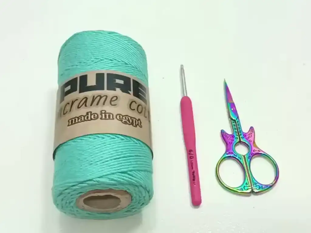 Essential materials for the crochet phone case project, including turquoise yarn, a 3.5mm crochet hook, and scissors.