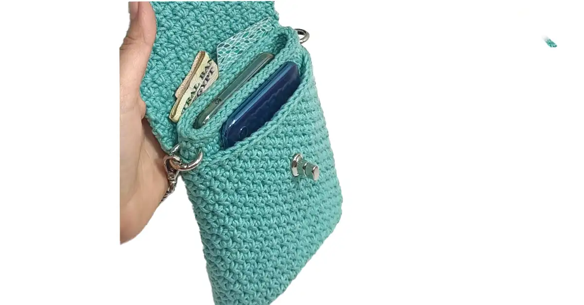 A stylish turquoise crochet phone case with strap and metal clasp closure, showcasing the completed project.