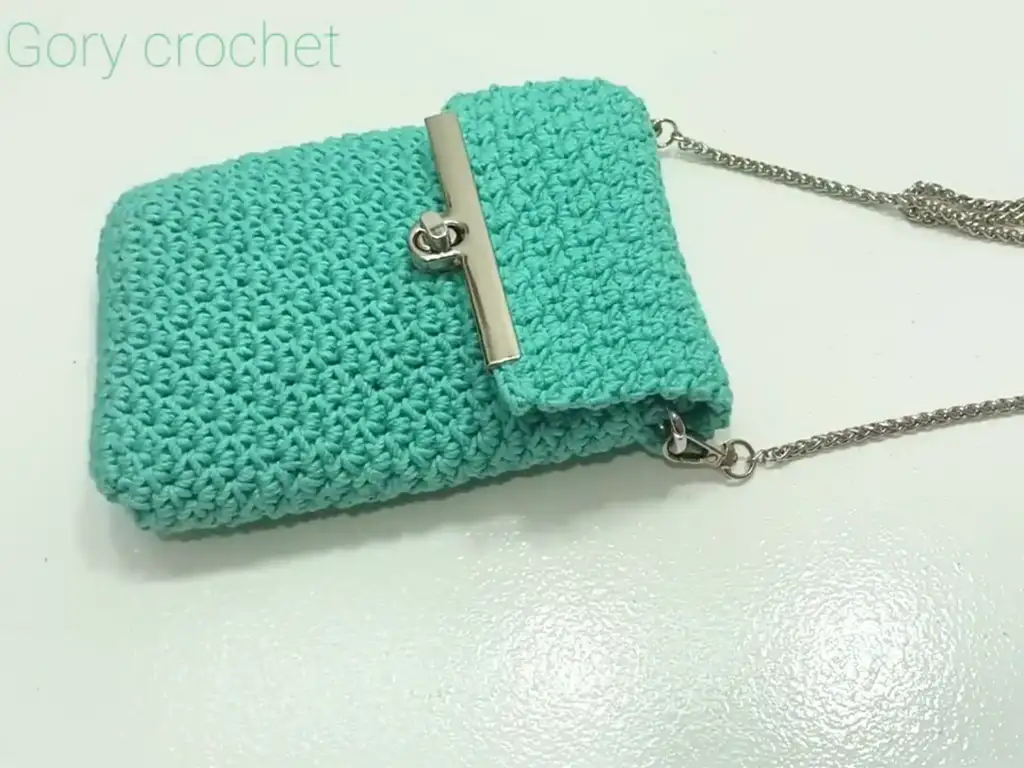 Stylish mint green crochet phone case with a metal clasp and a delicate silver chain strap.