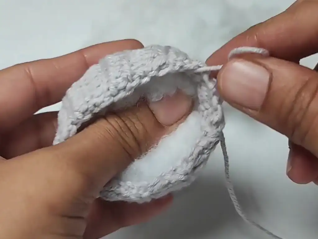 Hands stuffing a crochet pumpkin keychain with fiberfill.
