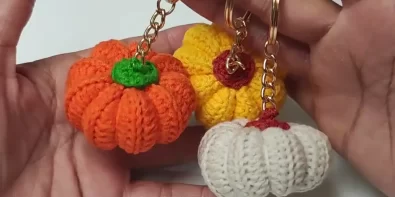 Three handmade crochet pumpkin keychains in orange, yellow, and cream, showcasing the finished project.