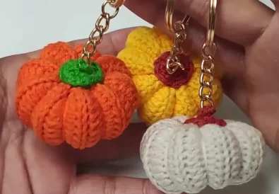 Three handmade crochet pumpkin keychains in orange, yellow, and cream, showcasing the finished project.