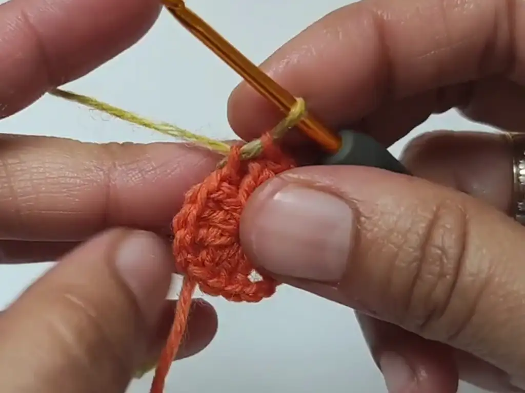 Hands joining a new color of yarn to a crochet square motif.