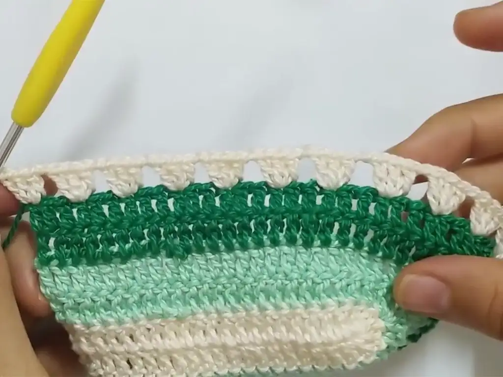 Adding a lace-like edging to the crochet top.