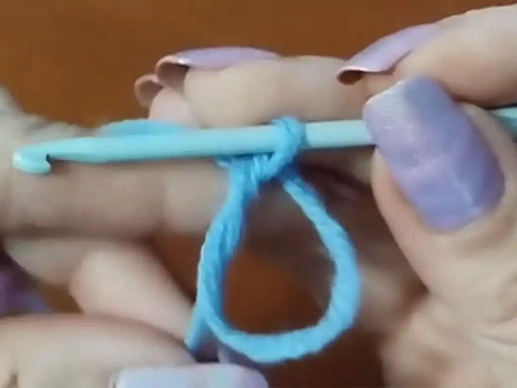 Close-up of a crochet hook making a slip knot, the first step of the crochet cloche hat pattern.