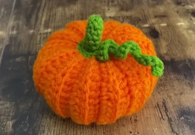 Adorable crocheted pumpkin with stem and vine, perfect for fall decorations.