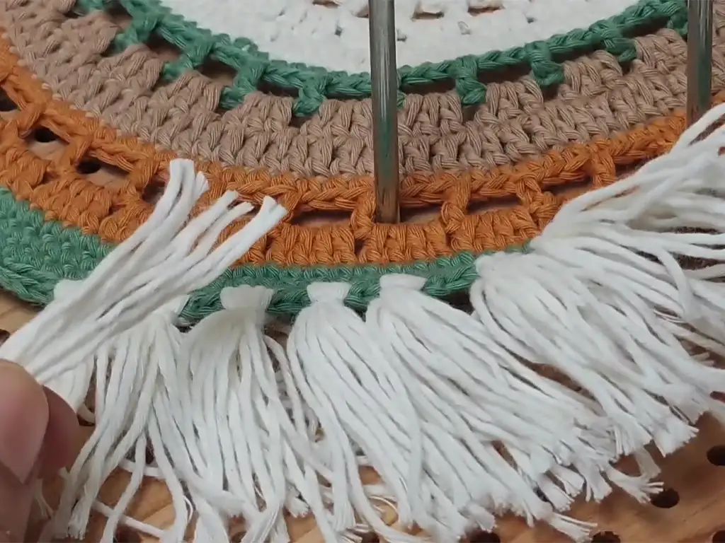 Creating tassels for the crochet placemat using white yarn.