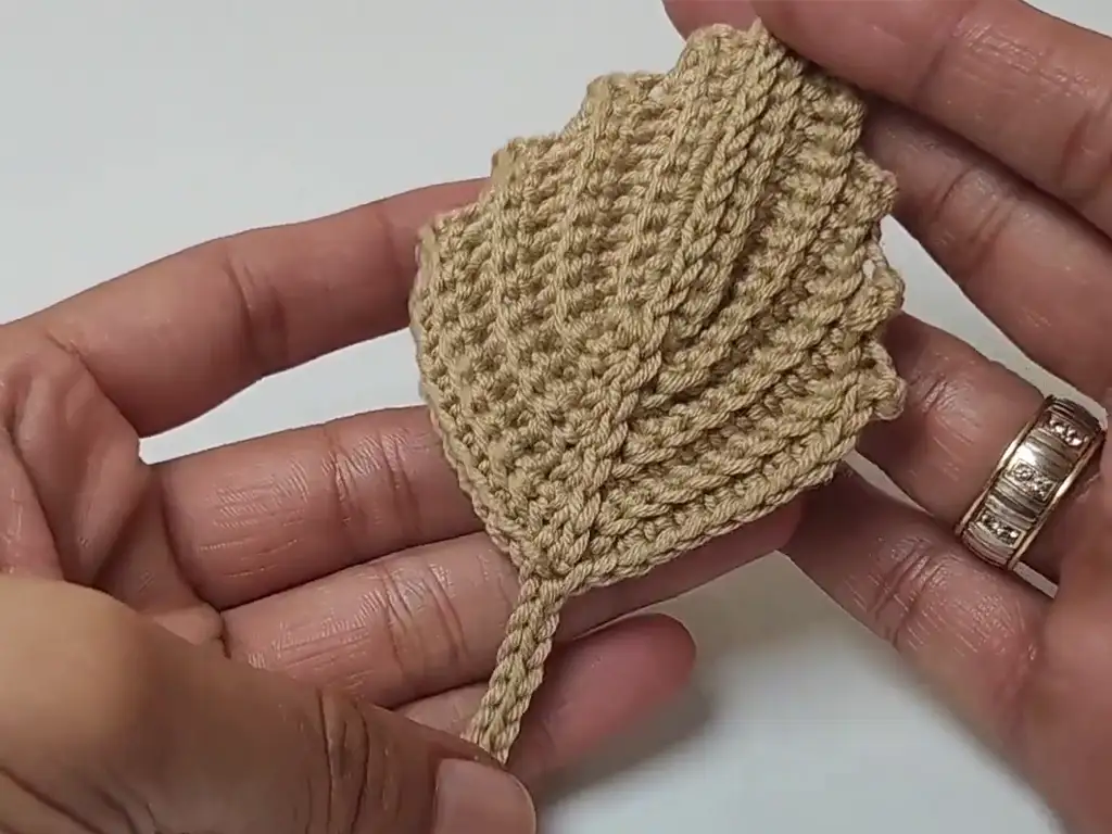 A finished crochet pumpkin leaf with a delicate stem, adding a realistic touch to the design.