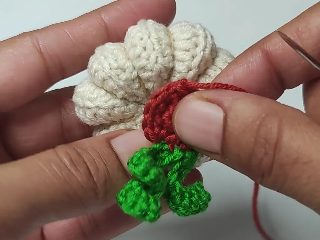Attaching crocheted stem and leaves to the pumpkin body.