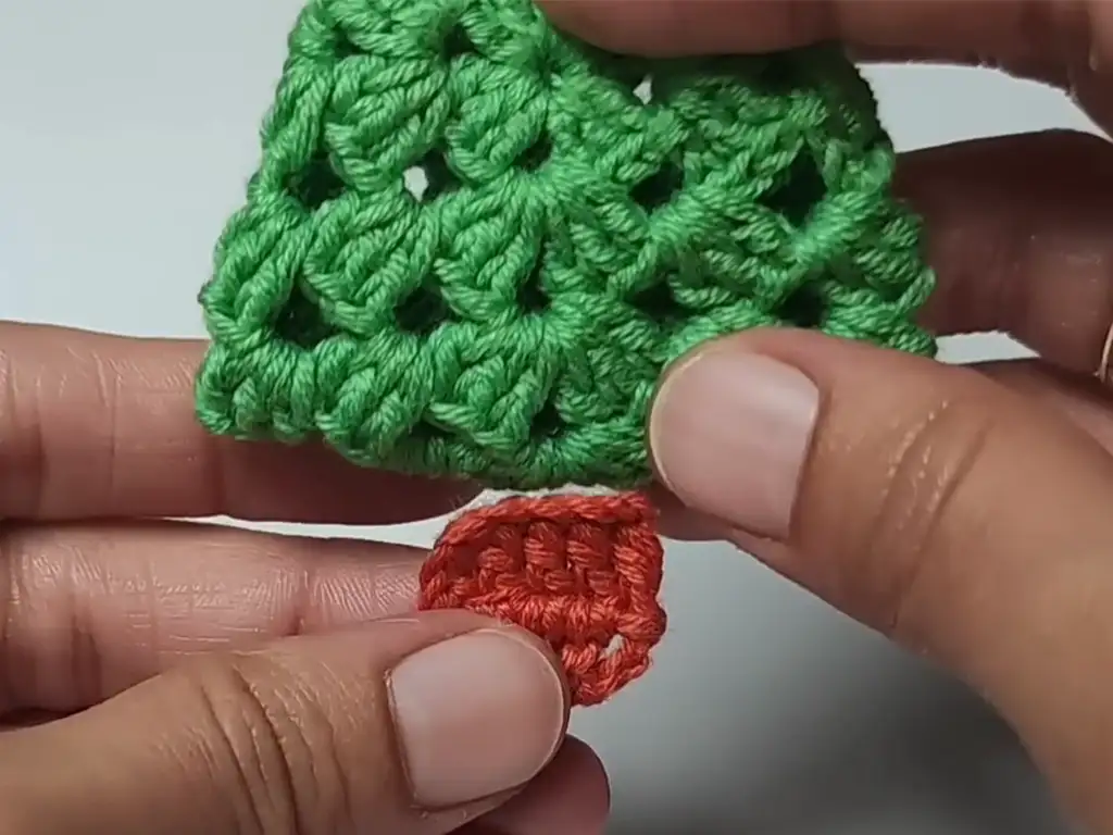 Attaching a small crocheted trunk to the bottom of the Christmas tree ornament.