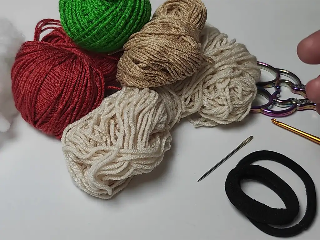 Yarn, stuffing, crochet hook, and hair tie - materials for a crochet project.