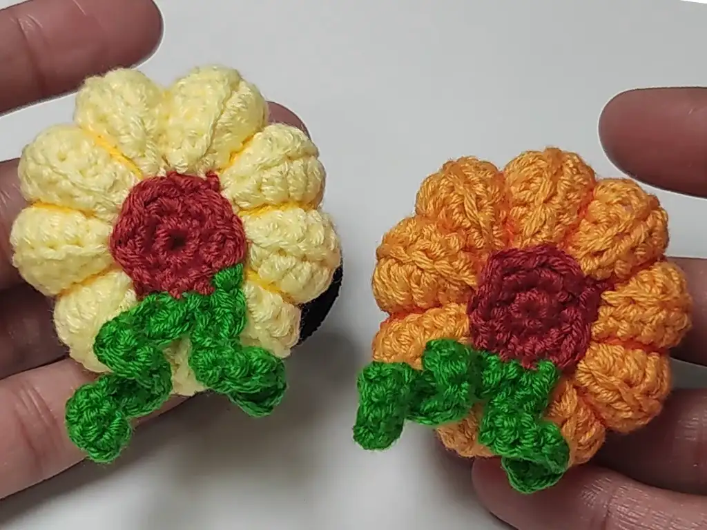 Two finished crochet pumpkin hair ties in orange and yellow.