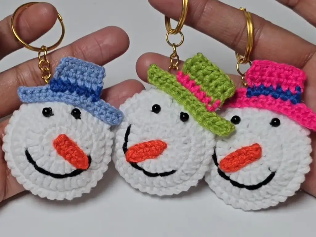 A display of completed crochet snowman keychains with different colored hats, showcasing customization options.