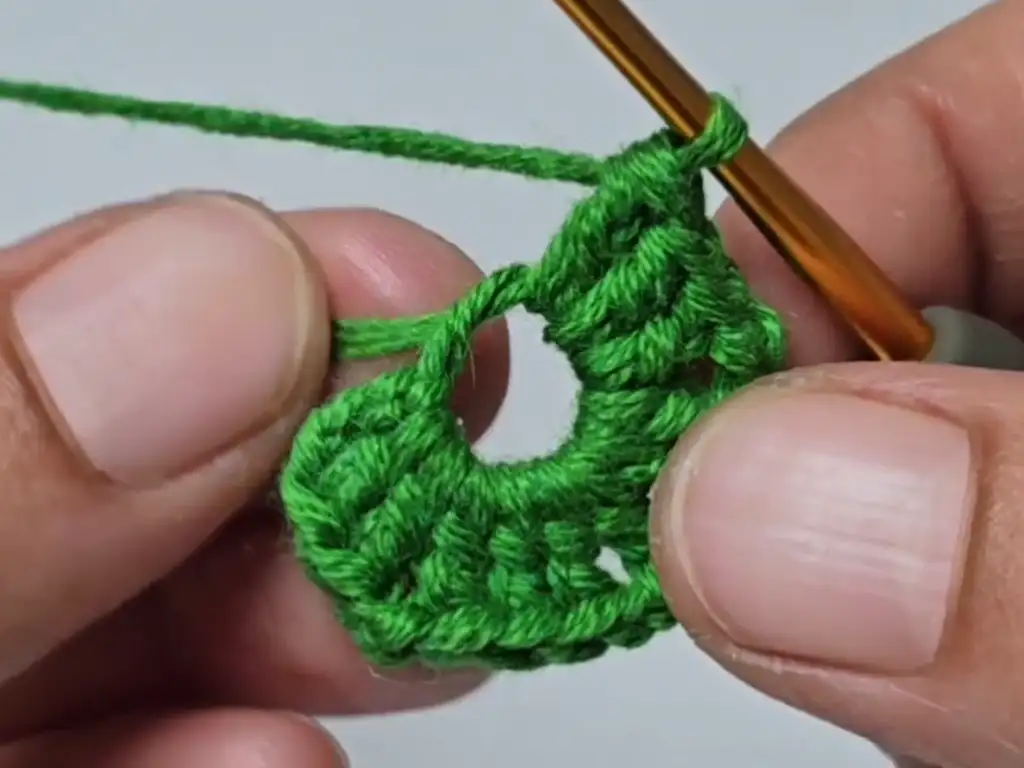 A crochet hook works the first round of stitches into a magic ring, forming the base of the crochet tree.