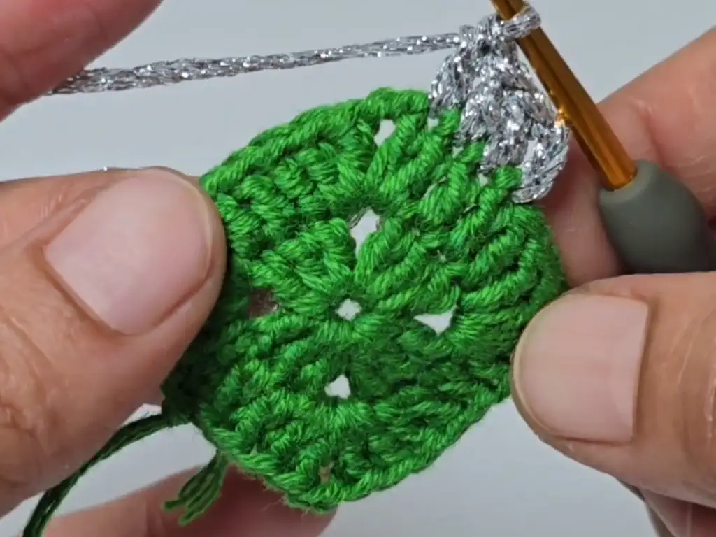 Incorporating sparkly silver yarn into the crochet Christmas tree pattern for a festive touch.