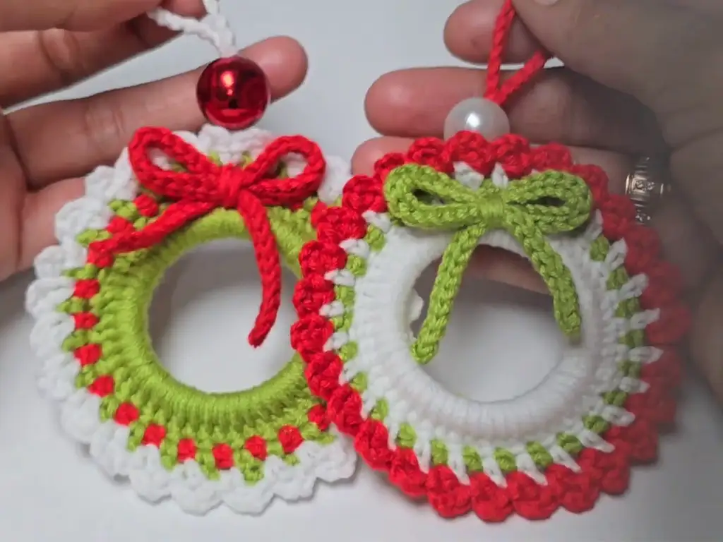 Two decorated crocheted Christmas wreaths, featuring bows and beads.