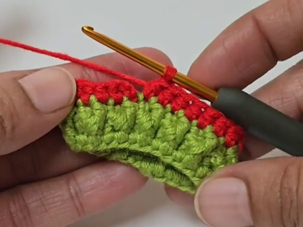 Crocheting the red brim of the Santa hat keychain using single crochet stitches.