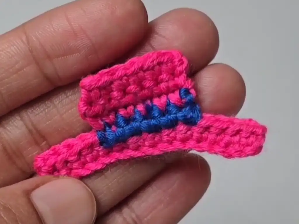 A completed colorful crochet snowman hat with a striped design.