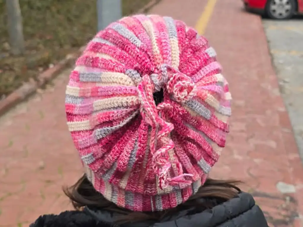  Child wearing pink and gray crochet beanie, back view with gathered top.
