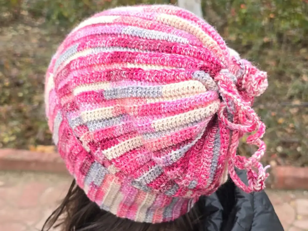 Top view of a pink and gray crochet beanie with gathered drawstring.