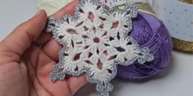 Close up of handmade crochet snowflake with silver sparkle details, perfect as a Christmas ornament.