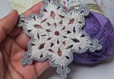 Close up of handmade crochet snowflake with silver sparkle details, perfect as a Christmas ornament.