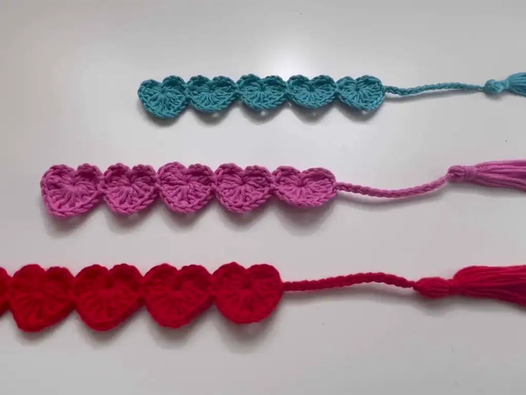 Three completed crochet heart bookmarks in red, pink, and blue, showcasing size variations.